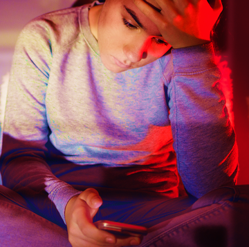 a young woman looking at her phone with her head in her hand a young woman looking at her phone with her head in her hand